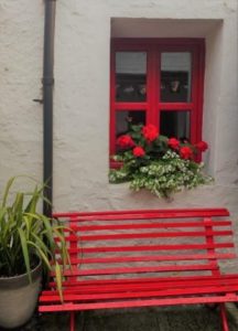 A red bench outside a cottage, Ireland, CozyMedley