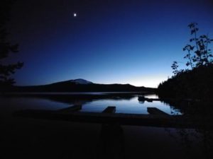 A moon rising over a lake